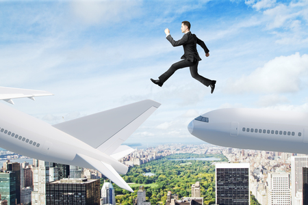 Businessman jumping on airplane on city background. Business travel and change concept.の写真素材