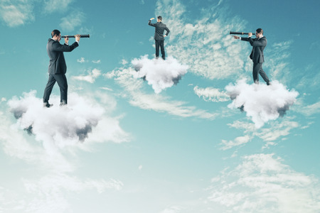 Businessmen on cloud looking into the distance with binoculars on sky background. Teamwork, vision and success conceptの写真素材