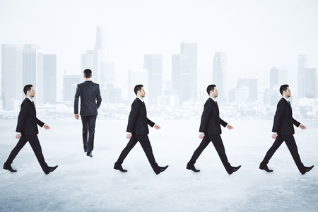 Rows of businessmen walking on light background. Teamwork and partnership conceptの写真素材