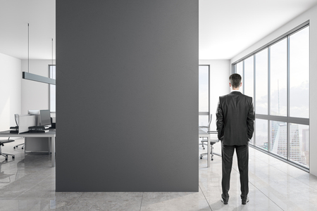 Young businessman in concrete office interior with copy space on wall and daylight. Mock up,の写真素材