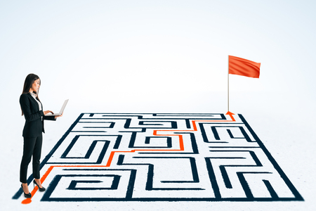 Businesswoman using laptop with maze and flag on white background. Challenge and communication conceptの写真素材