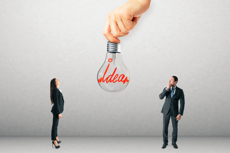 Businessman and woman with idea lamp on concrete wall background. Innovation and power conceptの写真素材