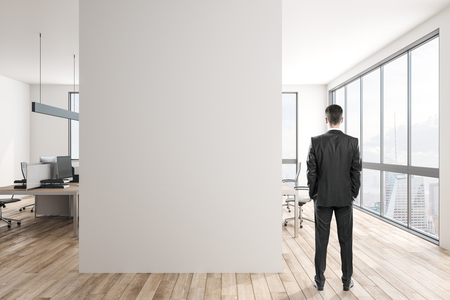 Young businessman in modern office interior with copy space on wall and daylight. Mock up,の写真素材