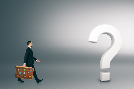 Businessman walking towards question mark on light background. Doubt and confused conceptの写真素材