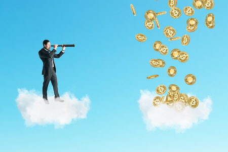 Young businessman on cloud looking at bitcoins with telescope. Forecast and cryptocurrency conceptの写真素材