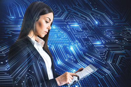 Attractive young businesswoman using tablet with circuit. Technology and computing concept. Double exposureの写真素材