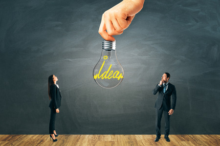 Businessman and woman with idea lamp on chalkboard wall background. Innovation and solution conceptの写真素材