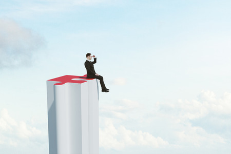 Businessman looking into the distance from jigsaw skyscraper on sky background with clouds. Research and cooperation concept. 3D Renderingの写真素材
