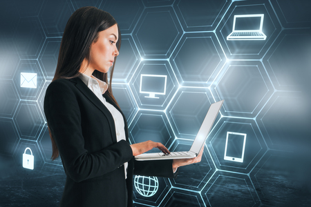 Attractive young businesswoman using laptop with digital interface. Future and computing concept. Double exposureの写真素材