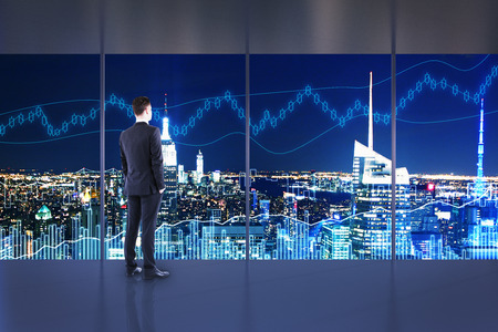 Trade and investment concept. Businessman in interior with night NYC view and forex chart. Double exposureの写真素材