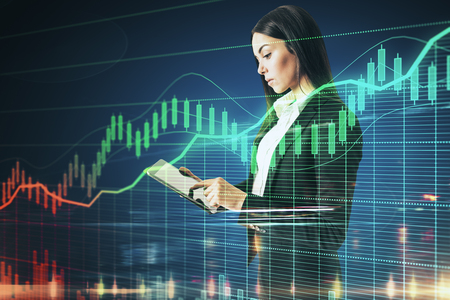Investment and money concept. Attractive young businesswoman using laptop with forex chart. Double exposureの写真素材