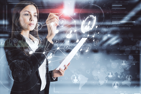 Attractive young businesswoman with document standing in blurry office with digital business interface. Innovation and finance concept. Double exposureの写真素材
