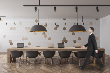 Side view of young businessman walking in modern office interior with concrete wall and wooden floor. Execuitve concept. 3D Renderingの写真素材