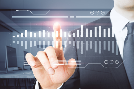Businessman hand pointing at glowing business chart in blurry office interior. Network and finance concept.の写真素材