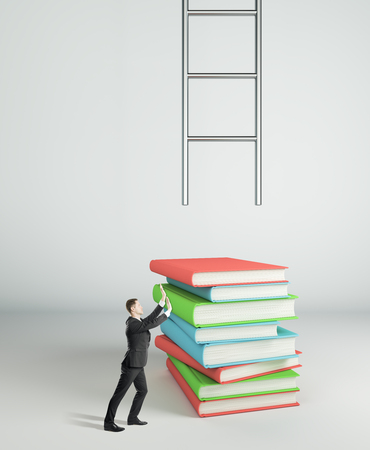 Businessman pushing book stack to climb ladder on white background. Education and growth concept.の写真素材