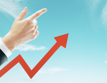 Businessman hand and red arrow pointing up on sky background. Growth and finance conceptの写真素材