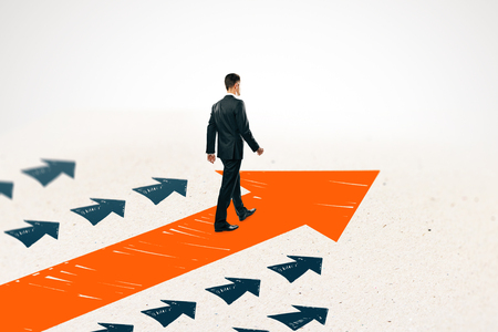 Side view of young businessman following drawn arrows on light background. Success and growth conceptの写真素材