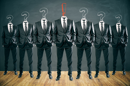 Row of question and exclamation mark headed businessmen standing in abstract chalkboard interior. Leadership and confidence conceptの写真素材