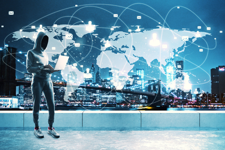 Young hacker on rooftop using laptop with digital map on night city background. Global virus and attack conceptの写真素材