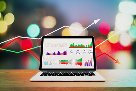 Close up of laptop with business charts on wooden desk and blurry bokeh background with arrows. Analysis and technology concept. 3D Renderingの写真素材