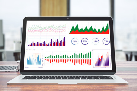Close up of laptop with business charts on wooden desk and blurry interior background. Finance and technology concept. 3D Renderingの写真素材