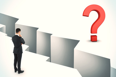 Thoughtful young businessman looking at gap with question mark. Challenge and solution concept.の写真素材
