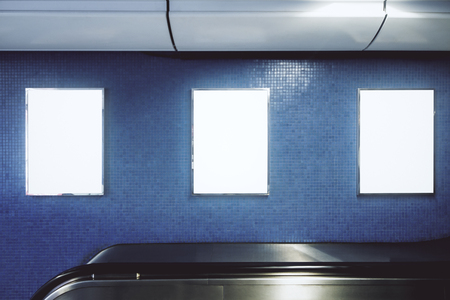 Front view of blank white underground banner on gray wall with escalator. Advertisement and urban concept. Mock upの写真素材