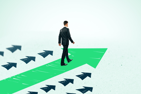 Side view of young businessman following drawn arrows on light background. Success and leadership conceptの写真素材