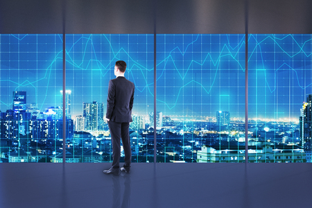 Businessman standing in abstract interior with night New York city view and forex chart. Office and broker concept.の写真素材