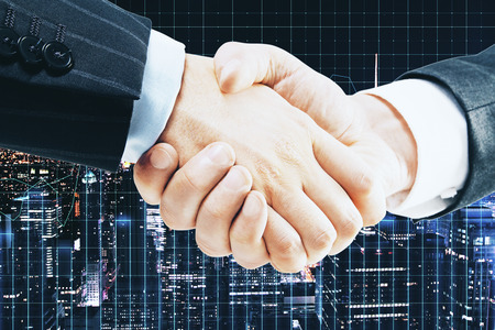 Side view and close up of handshake on glowing night city background with forex chart. Teamwork and stock concept. Double exposureの写真素材