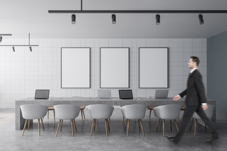 Side view of young businessman walking in modern office interior with empty posters. Mock up,の写真素材