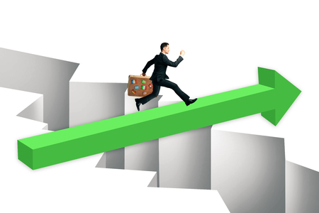 Businessman with travel suitcase running on green arrow over gap. Challenge and overcoming problems concept.の写真素材