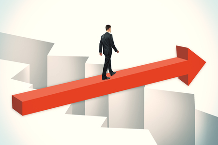 Businessman walking on red arrow over gap. Challenge and overcoming problems concept.の写真素材