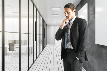 Attractive young european businessman standing in modern office interior.の写真素材