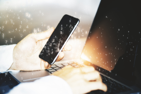 Hand using smartphone and laptop with binary code. Technology and computing conceptの写真素材