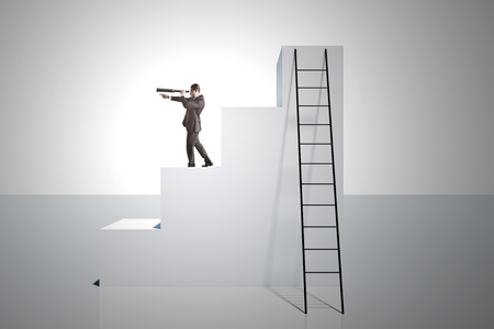 Businessman looking into the distance on top of stairs with ladder on white background. Vision and growth concept.の写真素材