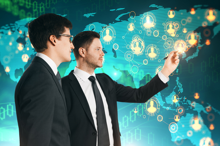 Two handsome young businessmen with abstract map interface. Global business and teamwork concept.の写真素材