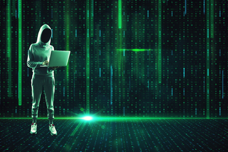Young hacker with laptop standing on abstract glowing binary code background. Hacking and attack concept.の写真素材