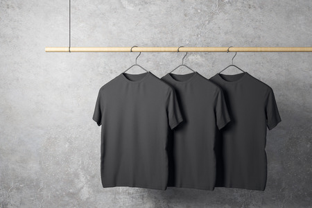 Empty three black tshirts on hanger. Concrete wall background. Design, store and style concept. Mock up, 3D Renderingの写真素材