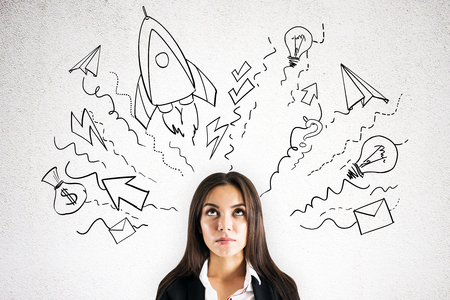 Portrait of attractive young european businesswoman with start up sketch thinking on concrete wall background. Startup and idea conceptの写真素材