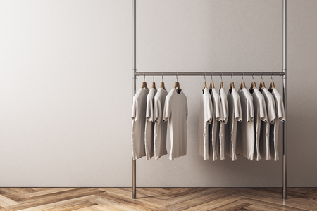 Hanger with row of tshirts in interior with empty copyspace on concrete wall. Design, fashion and ad concept. Mock up, 3D Renderingの写真素材