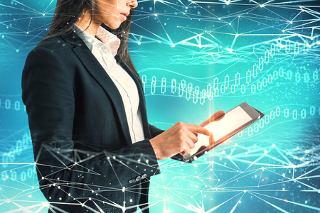 Side view of attractive young european adult using tablet on abstract blue polygonal background with digital forex interface. Innovation and trade conceptの写真素材
