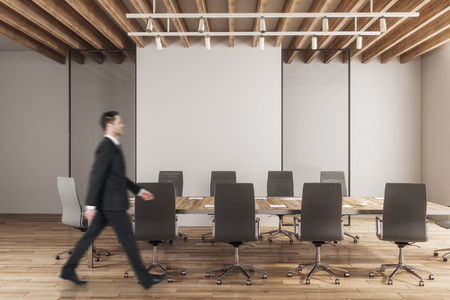 Side view of young businessman walking in modern meeting room interior with copy space. Mock up,の写真素材