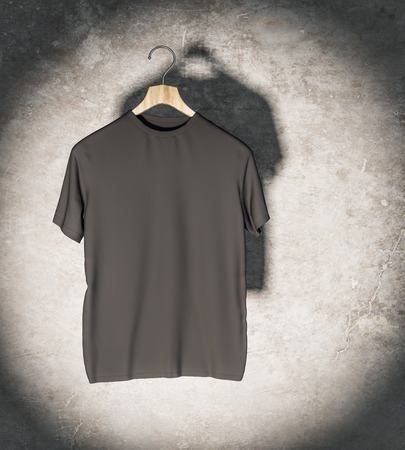Clean black t-shirt in spotlight hanging on concrete wall. Mockup and fashion concept. 3D Renderingの写真素材