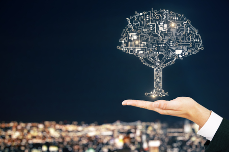 Hand holding abstract circuit tree on blurry night city background. Artificial intelligence and communication concept.の写真素材