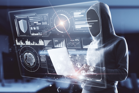 Hacker in hoodie using laptop with financial business interface on blurry office interior background. Analysis and hacking concept. Double exposureの写真素材