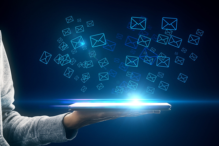 Hand holding tablet with glowing letter icons. E-mail marketing conceptの写真素材