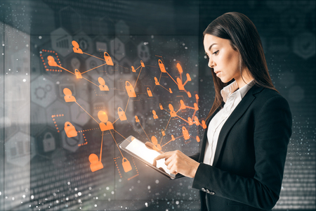 Side view of attractive young european adult using tablet on abstract blurry interior background with digital interface. Innovation and finance conceptの写真素材