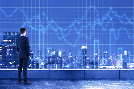 Young businessman on rooftop with forex chart grid and glowing night new york city background. Investment and finance concept. Double exposureの写真素材