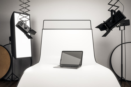 Photo studio with blank laptop on white background surrounded with professional equipment. Mock up, 3D Renderingの写真素材